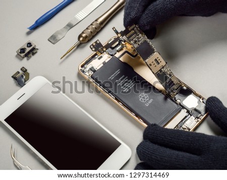 Technician or engineer disassembling components broken smartphone and take off logic board for repair or replace new smartphone logic board on desk  Royalty-Free Stock Photo #1297314469