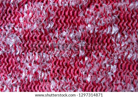 Close up pattern of a red and silver metal scourer.