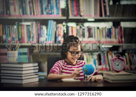 Portrait of a student girl studying at library with world globe looking map wold