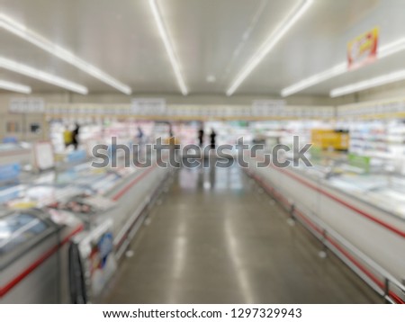 Abstract blurred supermarket aisle with colorful shelves and unrecognizable customers as background

