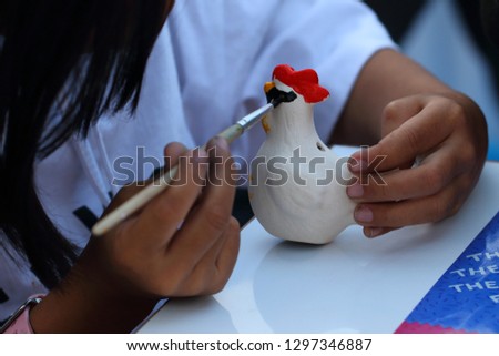 Painting on a doll chicken.