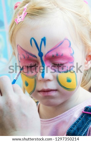 beautiful girl at a children's party with butterfly drawing on face