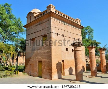 An ancient clay and mud building build by ancient people.a beautiful building surrounded by green trees and the blue sky on the background give more value to this picture.