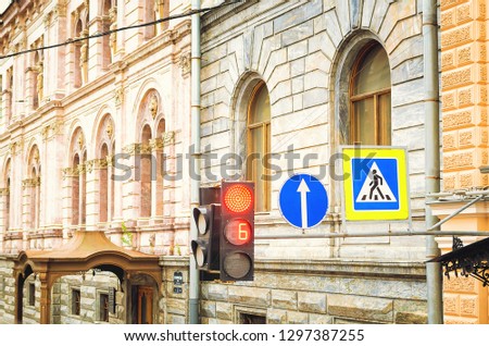 Red traffic light and pedestrian crossing road sign. Beautiful old architecture.