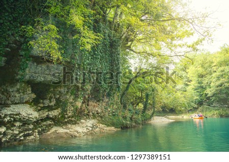 marvelous, fascinating bright photo in Martvili Canyon, the clear azure water of Georgia attracts, the start of the rafting, the tourists on inflatable boats float past stone rocks in the vines.