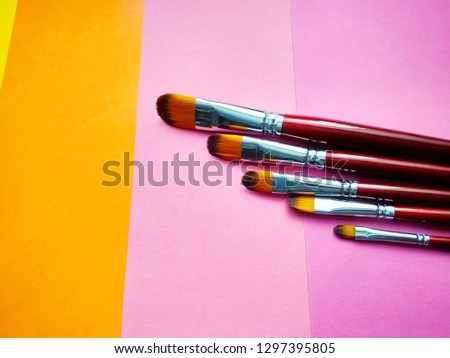 Background of colored paper with paint brushes