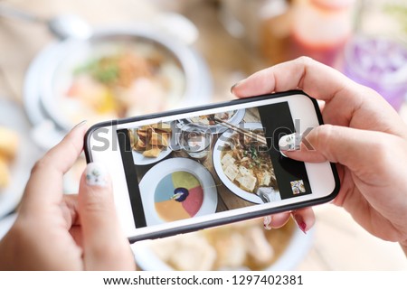 Woman taking a Food photography of Thai breakfast with smartphone. Home made food photo for social networks. Top view mobile phone photo of baked meat.