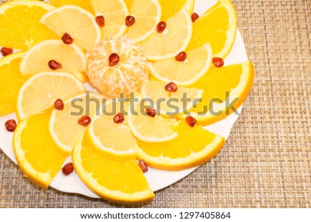 Sliced orange snd lemon decorated with pomegranate seeds . Decorative cutting of fruit 
