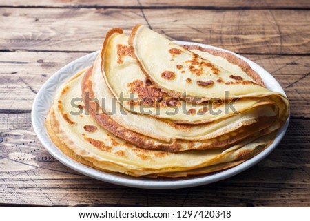 Thin pancakes on a plate. Wooden background. Close up