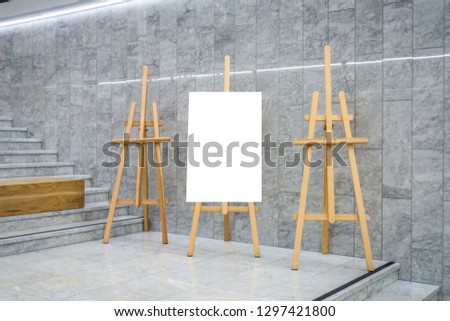 Blank art board canvas and three wooden easels in exhibition gallery