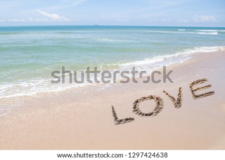 beautiful blue sea and sky with hand drawn word Love  on beach sand in sunny day. valentines background, love concept with copy space