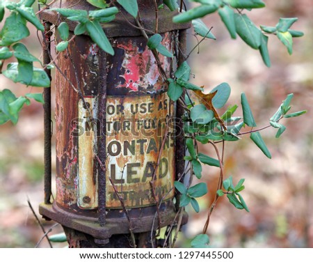  "Contains Lead" sign on side of abandoned Mobil gas pump at farm