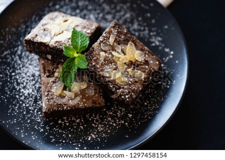 Brownie stack with almonds.A stack of chocolate brownies on wooden background with mint leaf on top, homemade bakery and dessert concept.