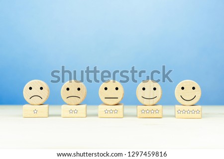 Customer service experience and satisfaction survey concept with facial expressions icon (negative, neutral, positive) and five star symbol on wooden cube on table. copy space