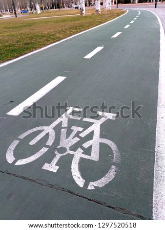 CLOSE UP OF A WHITE PAINTING OF A BICYCLE ON THE GREEN ASPHALT OF THE ROAD THAT MEANS A PLACE IN THE CITY TO CYCLE RIDERS ´ BICYCLES ON A GREEN BACKGROUND.