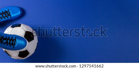 Soccer ball under soccer players feet on blue background