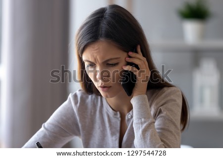 Serious concerned woman talking on phone helping solving problem customer complaint, stressed worried girl discussing business issue speaking by cell mobile making call having difficult conversation Royalty-Free Stock Photo #1297544728