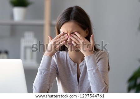 Tired teen girl rubbing dry irritable eyes feel eye strain tension migraine after computer work, exhausted young woman worker student relieving headache pain, bad weak blurry vision, eyesight problem Royalty-Free Stock Photo #1297544761