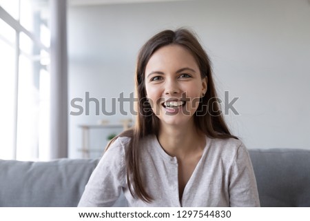 Smiling teen girl speaking by video call distance job interview looking at camera talking to webcam, female vlogger recording vlog at home, teacher student teach study online, head shot portrait Royalty-Free Stock Photo #1297544830