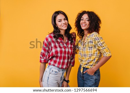Girlfriends put on similar shirts to look cute on photo shoot. Portrait of joyful brunette with brown eyes