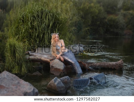 mythical attractive siren with a long tail, covered with scales, the sea princess with a wreath of shells plays in the river by the green grass, waves the water with a fin, bright colors in the photo