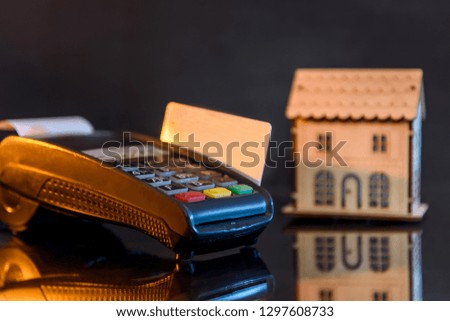 Terminal with credit card and wooden house model