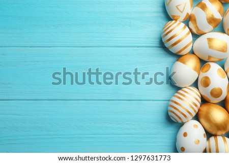Traditional Easter eggs decorated with golden paint on wooden background, top view. Space for text