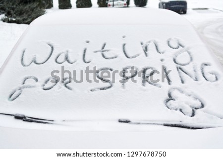Waiting for spring. The inscription on the windshield of a red car. The concept of cold spring, the end of winter Royalty-Free Stock Photo #1297678750