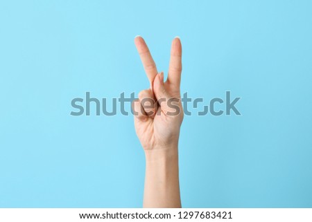 Woman showing K letter on color background, closeup. Sign language