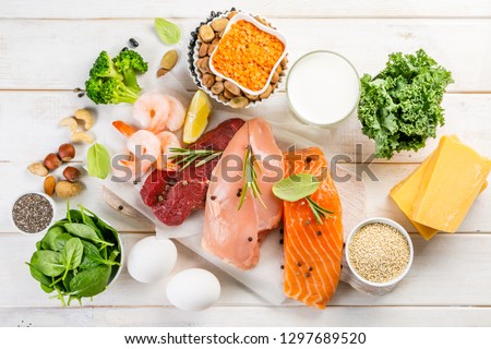 Selection of animal and plant protein sources - fish, meat, beans, cheese, eggs, nuts and seeds, kale, on wood background Royalty-Free Stock Photo #1297689520