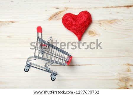 shopping trolley and read heart on wooden background