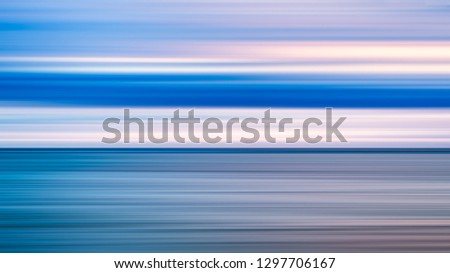 Abstract art background of blue sea and cloudy sunrise sunset sky over it. Motion blur sea water and sky with blue and red clouds.