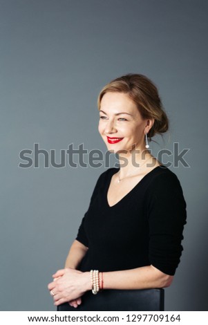 Portrait of beautiful woman in a black dress against grey background Royalty-Free Stock Photo #1297709164