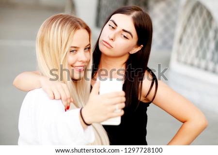 Close up lifestyle selfie portrait of two young positive woman having fun and making selfie, teenage hipster trendy clothes, long hairs, fresh make up. happy together. sisters, friends 