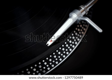 Closeup of turntable needle on background with vintage black LP record