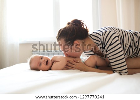 Mom and baby together, mom kisses and plays with the baby for 6 months. Concept motherhood and lifestyle