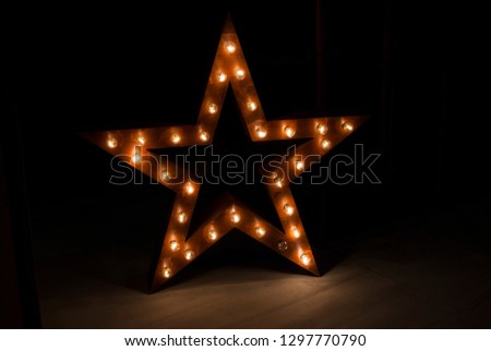 Element fot your desing Yellow five-poin Star. Decorative star with lamps. Large wooden star with a large amount of lights in front of dark concrete background.  Backdrop of a glowing star - Image
