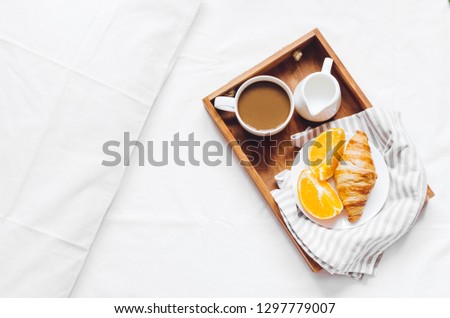 Romantic Valentines Day breakfast in bed, tray with fresh croissant, cup of coffee espresso with milk and fresh oranges. Good morning concept. Enjoy slow life. Top view. Copy space.