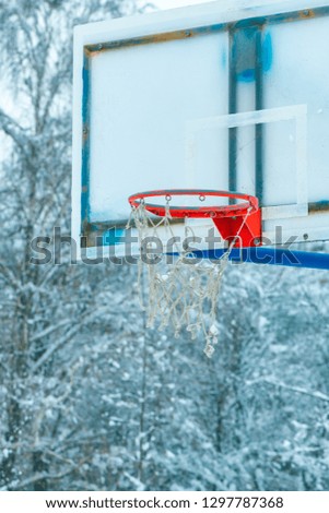 Frozen outdoor basketball hoop in winter snow on empty sport playground