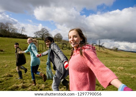Outdoor portrait young friends holding hands on walk in countryside