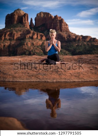 A woman meditating in front of Cathedral rock and a reflecting pool in Sedona Arizona Royalty-Free Stock Photo #1297791505