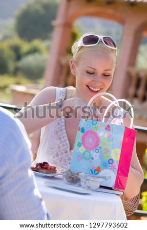 Smiling woman showing man shopping at outdoor cafe