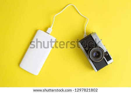 Flat lay of vintage photo camera and power bank charger retro vs modern minimal creative concept.