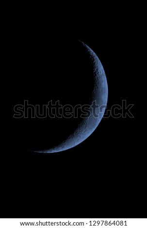 Blue Crescent Moon in black sky.
