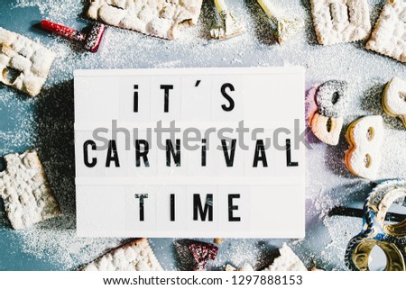 Carnival concept, a lightbox with message " it's carnival time" illuminate circled by cookies and sweeties typical of carnival, like italian sfrappole or Chiacchiere, carnival fried pastry,flatlay