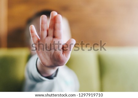 Close up shop of little baby boy's palm as a stop sign. Copy space for you text. Kid reaching for high five.
