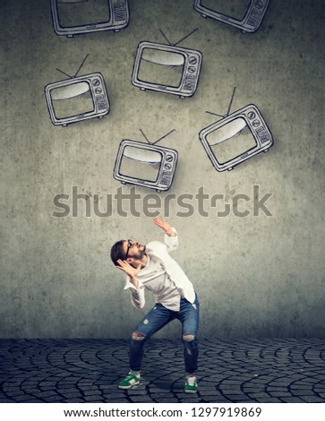Multiple TV sets falling on a strssed scared young man 