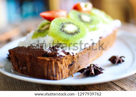 Fruit cake decorated with sliced fresh kiwi and strawberry.