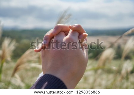 Close-up of a couple holding hands at the peak of Oreum of at Jeju Island, South Korea                               