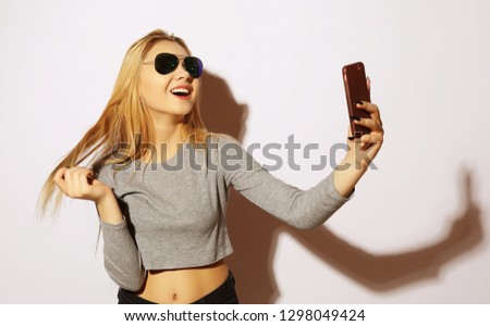 Pretty hipster girl making selfie over white background.Studio shot.